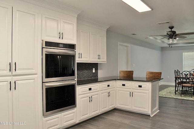 kitchen featuring stainless steel double oven, white cabinetry, and kitchen peninsula