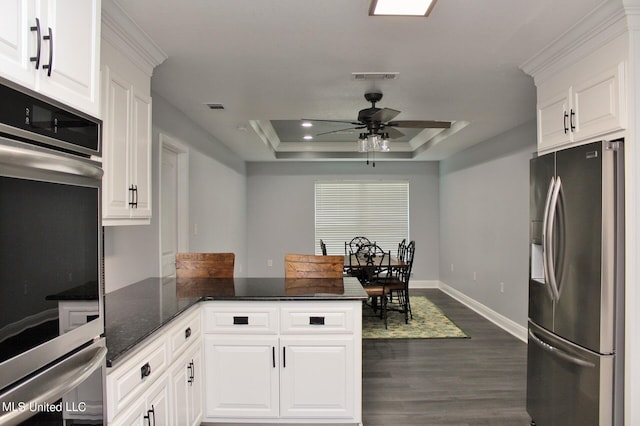 kitchen with white cabinetry, stainless steel appliances, a tray ceiling, and dark hardwood / wood-style flooring