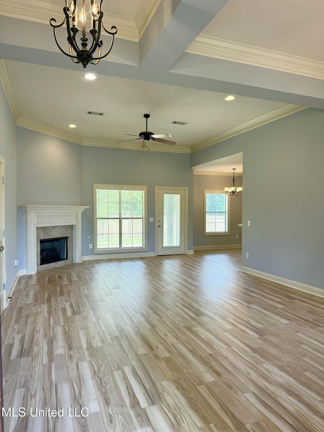 unfurnished living room with ornamental molding, ceiling fan with notable chandelier, a high end fireplace, and light hardwood / wood-style flooring