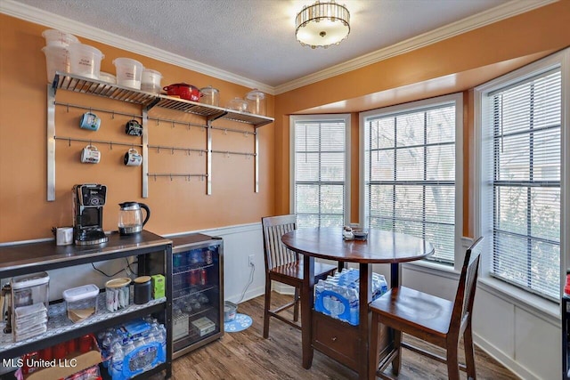 dining space featuring hardwood / wood-style flooring, ornamental molding, beverage cooler, and a textured ceiling