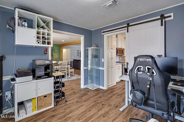 office featuring a barn door, a textured ceiling, and light hardwood / wood-style floors