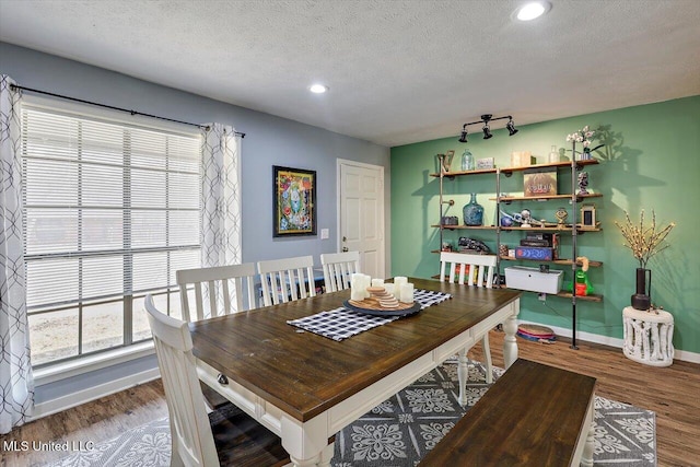 dining area with wood-type flooring and a textured ceiling