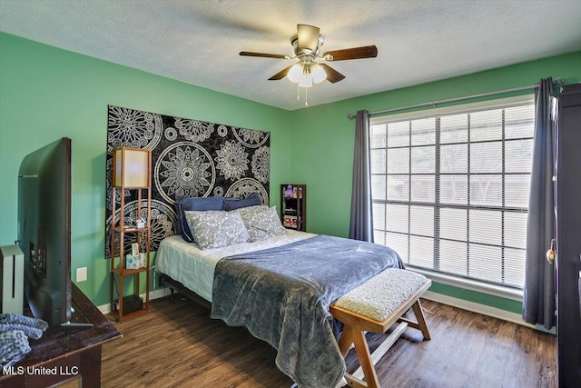 bedroom featuring dark hardwood / wood-style flooring, ceiling fan, and a textured ceiling