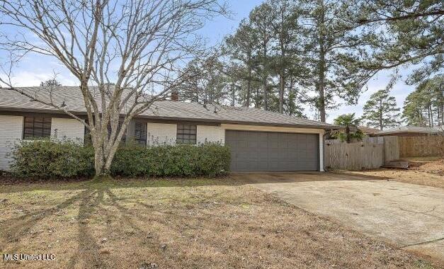 ranch-style home featuring a garage and a front lawn