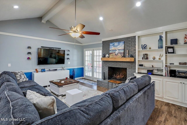 living room featuring dark wood-type flooring, vaulted ceiling with beams, crown molding, ceiling fan, and a fireplace