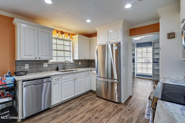 kitchen with sink, white cabinetry, hardwood / wood-style floors, stainless steel appliances, and light stone counters