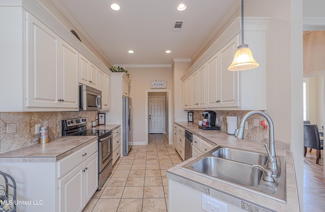127 Palin Dr, Madison, MS 39110 - kitchen featuring appliances with stainless steel finishes, white cabinets, ornamental molding, tasteful backsplash, and recessed lighting