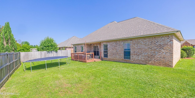127 Palin Dr, Madison, MS 39110 - back of house with a trampoline, a wooden deck, a fenced backyard, brick siding, and roof with shingles