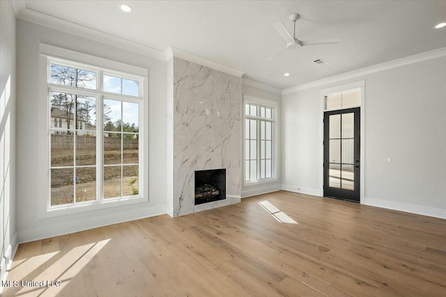 unfurnished living room featuring a premium fireplace, ornamental molding, wood finished floors, and recessed lighting