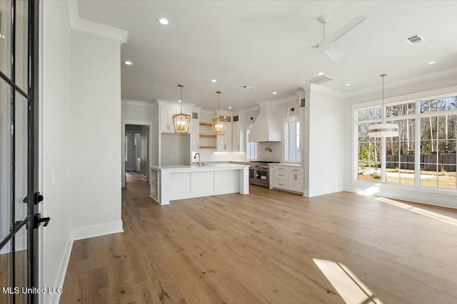 kitchen featuring custom exhaust hood, visible vents, light wood-style floors, ornamental molding, and white cabinetry