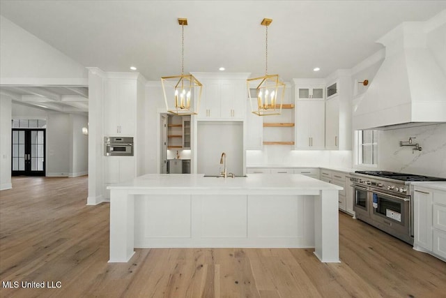 kitchen featuring light wood finished floors, an island with sink, custom exhaust hood, stainless steel appliances, and a sink