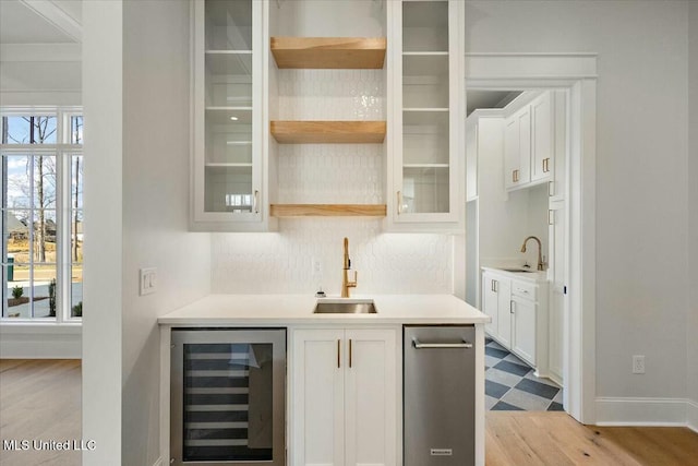 bar with beverage cooler, a sink, and a healthy amount of sunlight