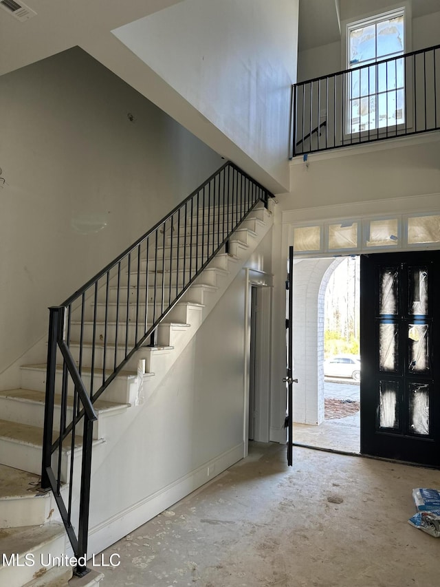 entryway with a towering ceiling, french doors, and concrete floors