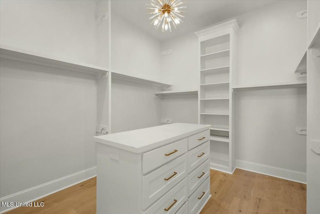 walk in closet with light wood-style floors and a notable chandelier