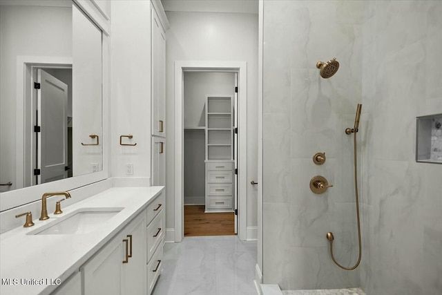 full bath with vanity, baseboards, marble finish floor, a marble finish shower, and a walk in closet