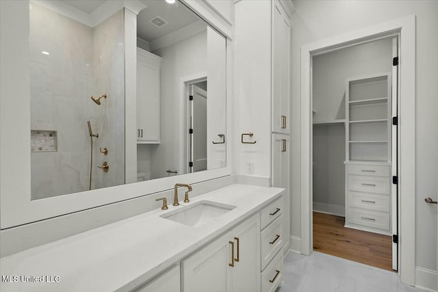 bathroom with a walk in shower, visible vents, vanity, and baseboards