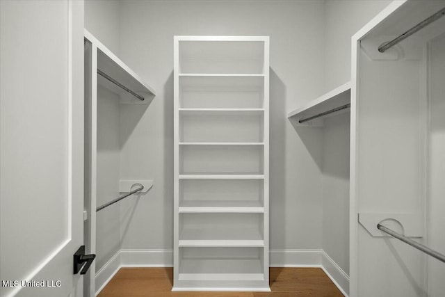 walk in closet with wood finished floors