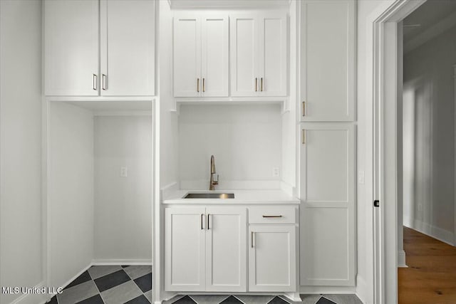 bar featuring dark floors, baseboards, and a sink