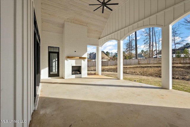 view of patio / terrace with a ceiling fan, fence, and exterior fireplace