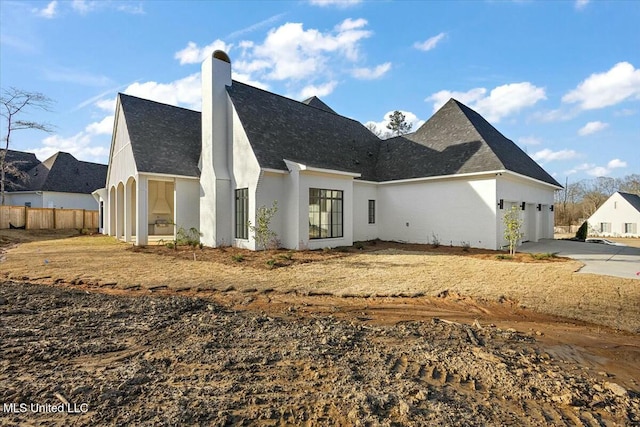 exterior space with a garage, driveway, a chimney, fence, and stucco siding