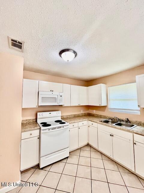 2614 George St, Gulfport, MS 39503 - kitchen featuring white appliances, white cabinets, a sink, a textured ceiling, and light countertops
