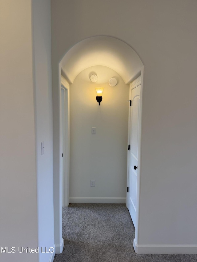 corridor with baseboards, arched walkways, and carpet