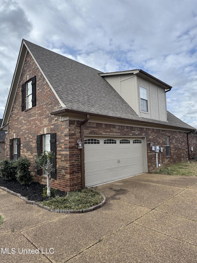 view of side of property with brick siding, concrete driveway, and roof with shingles