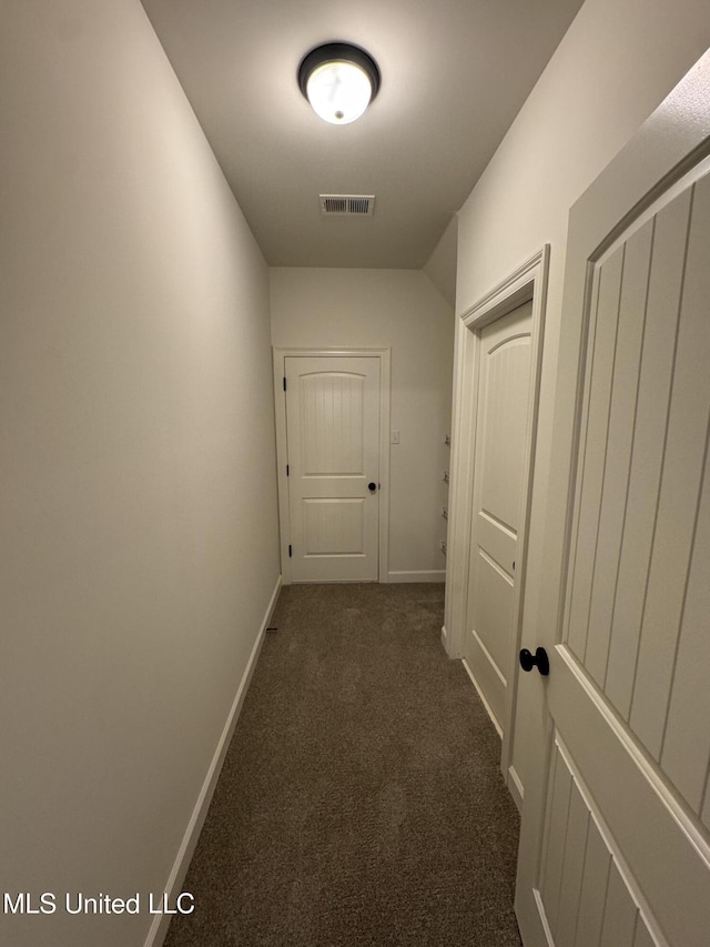 corridor featuring baseboards, visible vents, and dark colored carpet