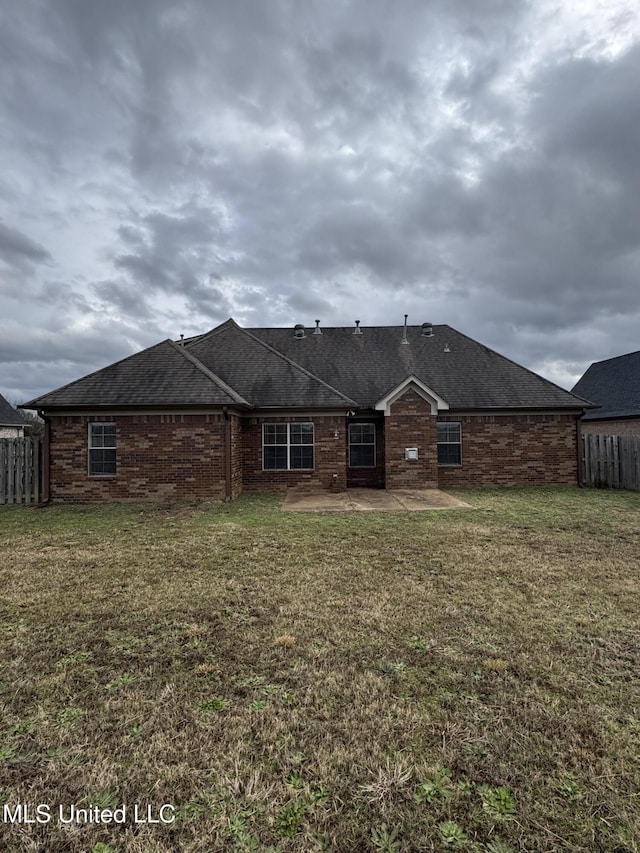 rear view of property featuring brick siding, fence, a lawn, and a patio area