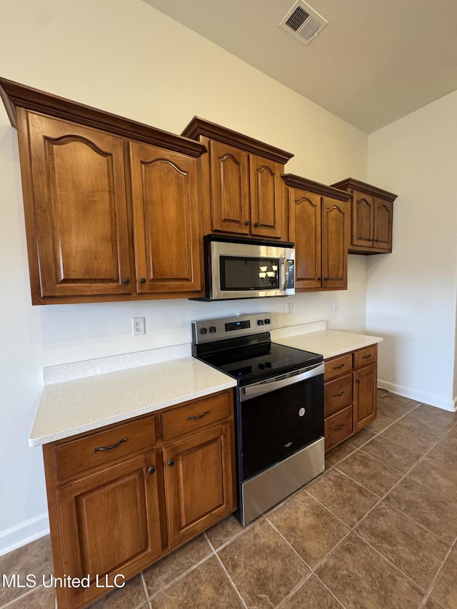 kitchen with dark tile patterned floors, visible vents, stainless steel appliances, and baseboards