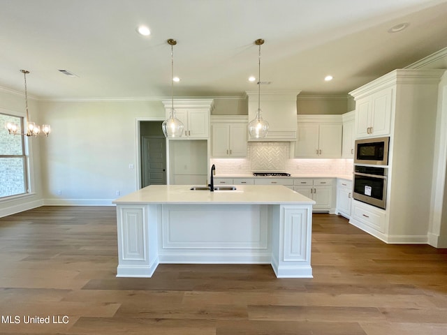 kitchen featuring white cabinets, stainless steel appliances, and a center island with sink