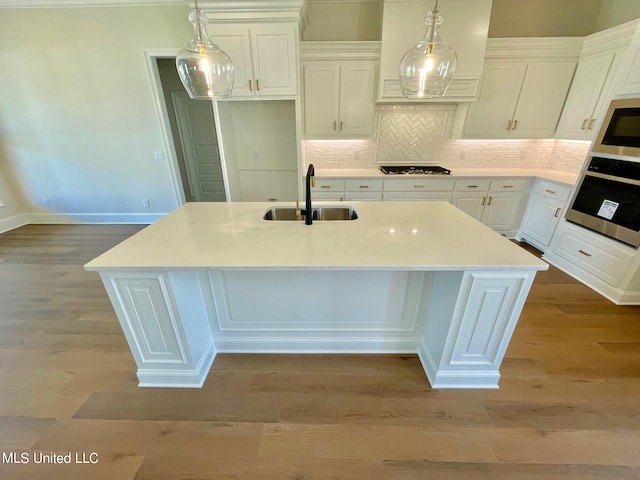 kitchen with appliances with stainless steel finishes, white cabinets, a kitchen island with sink, and sink