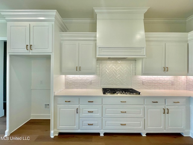 kitchen with decorative backsplash, stainless steel gas cooktop, dark hardwood / wood-style floors, custom range hood, and white cabinetry