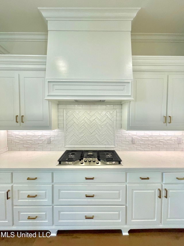 kitchen featuring stainless steel gas cooktop, crown molding, white cabinets, and tasteful backsplash