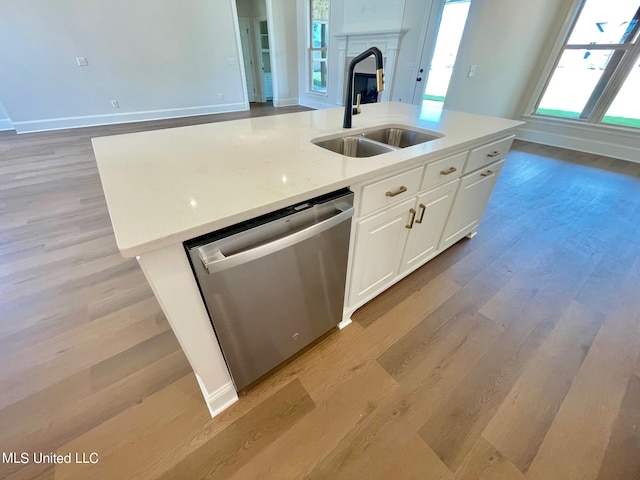 kitchen with a center island with sink, white cabinetry, stainless steel dishwasher, light wood-type flooring, and sink