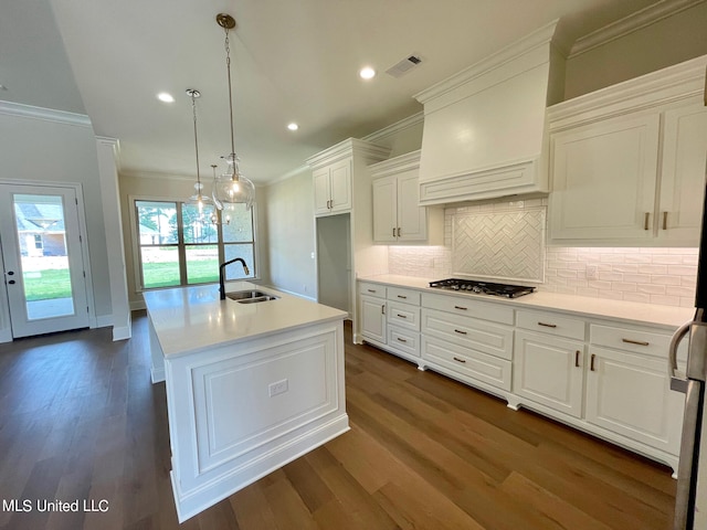 kitchen with sink, an island with sink, decorative light fixtures, crown molding, and dark hardwood / wood-style floors