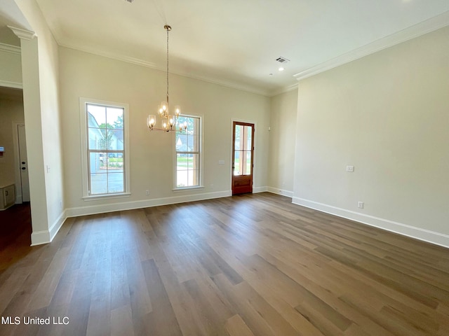 empty room with crown molding, a notable chandelier, and dark wood-type flooring