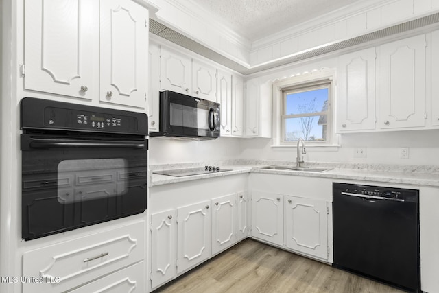 kitchen with white cabinetry, black appliances, crown molding, and a sink