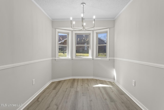 unfurnished dining area with a textured ceiling, ornamental molding, wood finished floors, and a chandelier