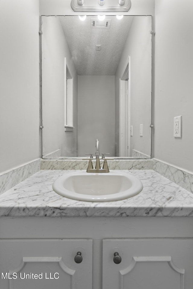 bathroom with visible vents, a textured ceiling, and vanity