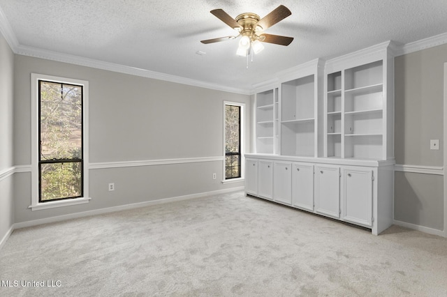 spare room featuring light carpet, a textured ceiling, and crown molding