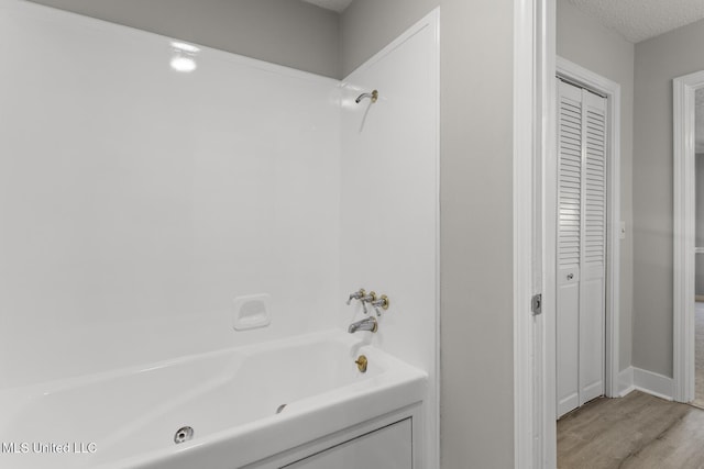 full bathroom featuring a closet, a textured ceiling, wood finished floors, and shower / bathtub combination