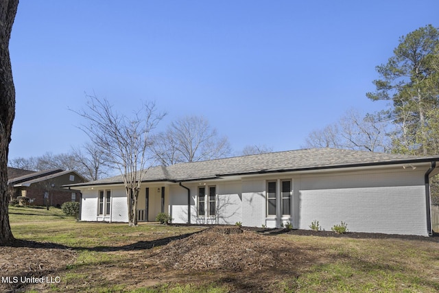 view of front of property with brick siding, a front yard, and a shingled roof