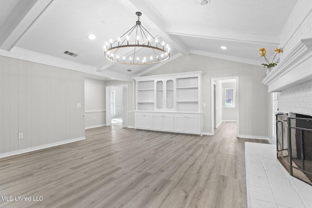 unfurnished living room with visible vents, vaulted ceiling with beams, light wood-type flooring, a fireplace, and an inviting chandelier