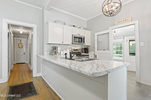 409 Coleman St, Como, MS 38619 - kitchen with appliances with stainless steel finishes, ornamental molding, white cabinets, light stone countertops, and a chandelier