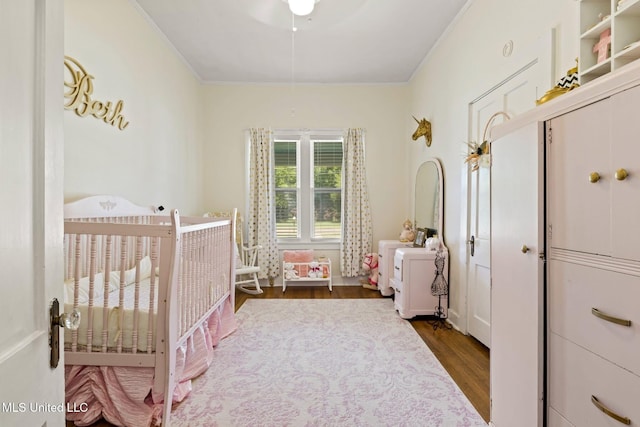409 Coleman St, Como, MS 38619 - bedroom featuring dark wood-style flooring, crown molding, and a crib
