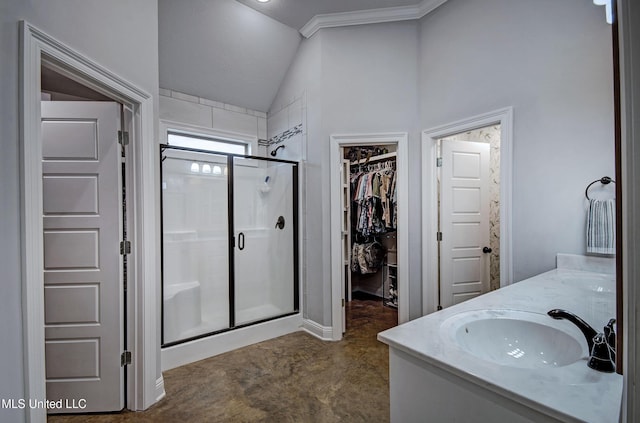 bathroom with double vanity, a walk in closet, a shower stall, a sink, and vaulted ceiling