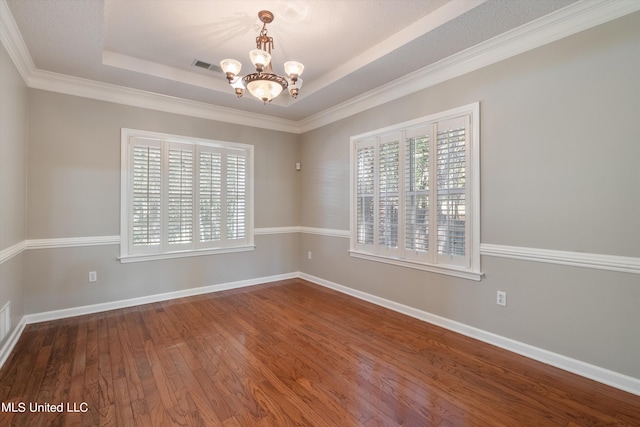 spare room featuring crown molding, a notable chandelier, a raised ceiling, and hardwood / wood-style floors