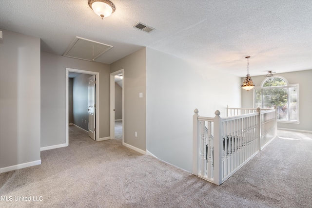 corridor featuring light carpet and a textured ceiling