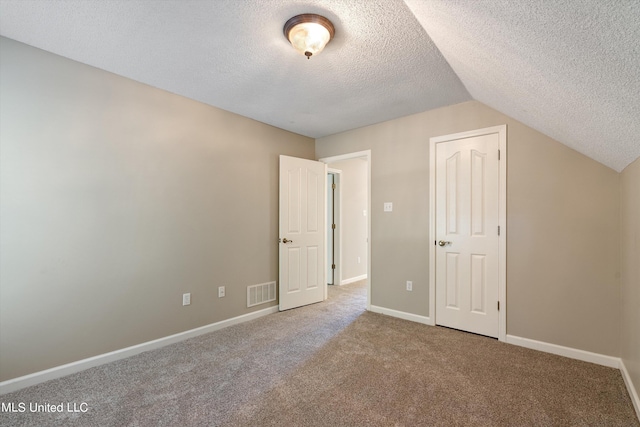 unfurnished bedroom featuring lofted ceiling, a textured ceiling, a closet, and carpet flooring